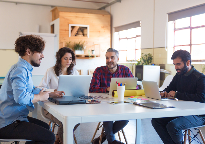 creative startup team working together on laptops, collaborating on ideas in a modern workspace